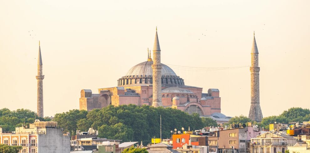 View of the iconic Hagia Sophia surrounded by İstanbul's urban landscape during sunset.