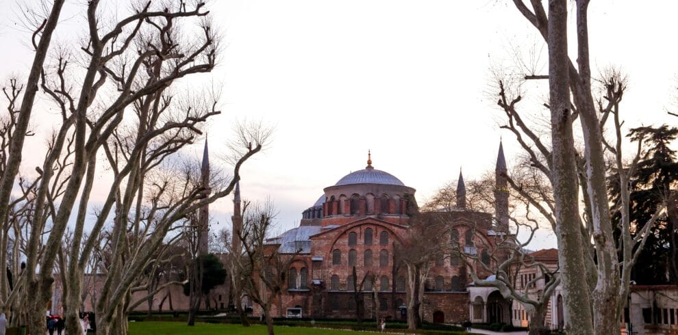 Explore the historic Hagia Sophia surrounded by bare trees at dusk, showcasing its stunning architecture.